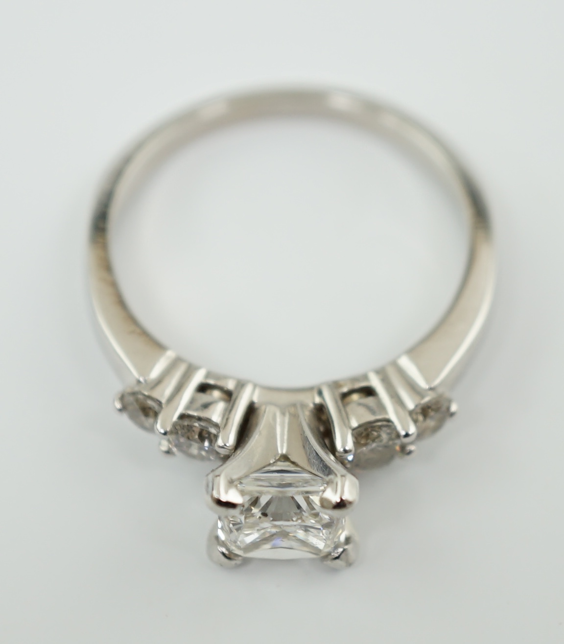 A modern 14k white gold and single stone diamond set ring, with four stone diamond set shoulders